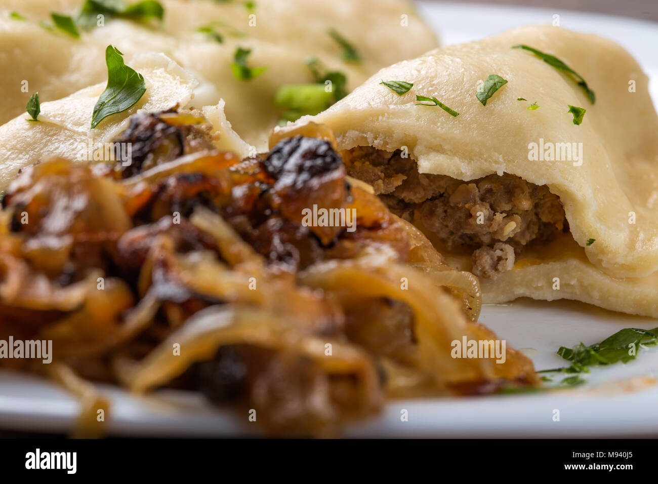 Pierogi, pyrohy o gnocchi, riempiti con carne di manzo servita con cipolla fritti sulla piastra Foto Stock