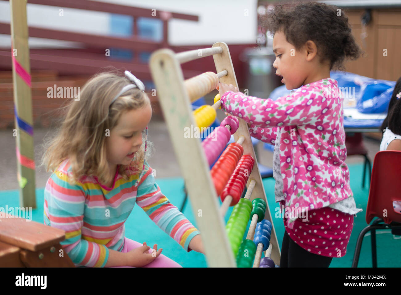 Due ragazze a giocare con un abaco presso una scuola materna nel Warwickshire, Regno Unito Foto Stock