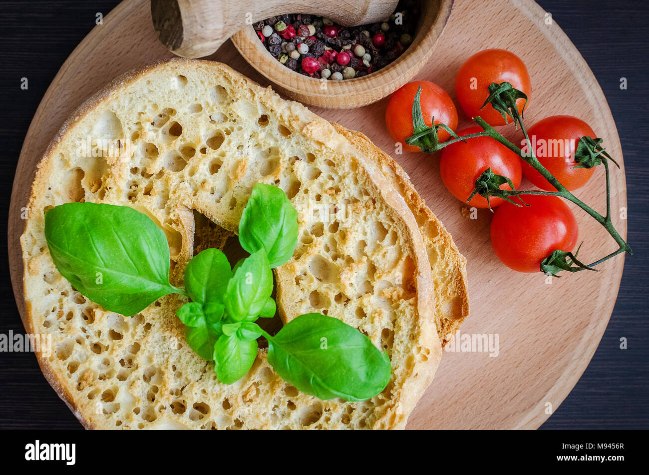 Italiano di pane secco Friselle sulla tavola di legno con pomodori ciliegia, il basilico e il pepe. Il cibo italiano. Una sana alimentazione vegetariana. Foto Stock