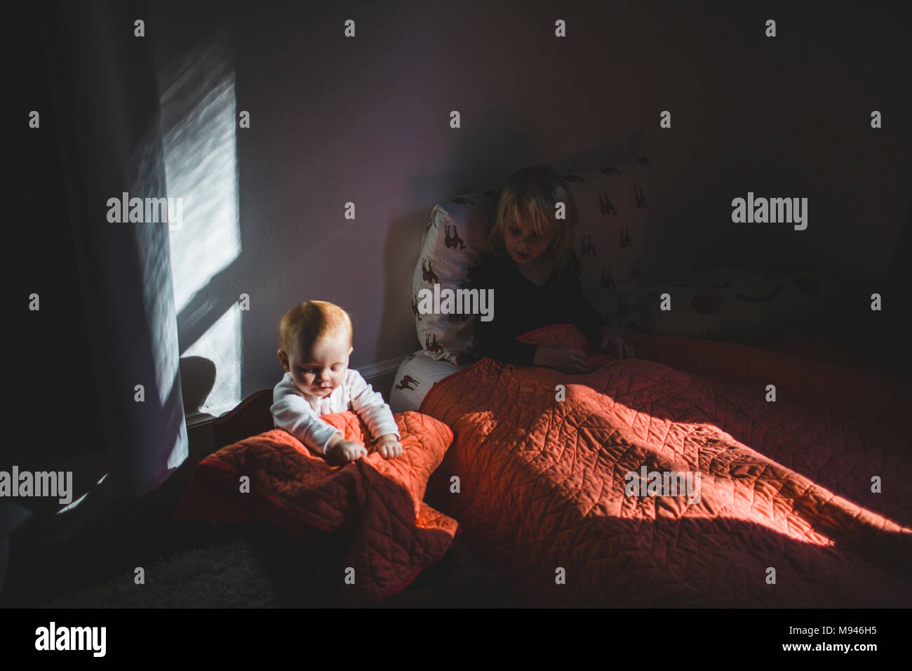 La ragazza e il bambino sotto le coperte Foto Stock