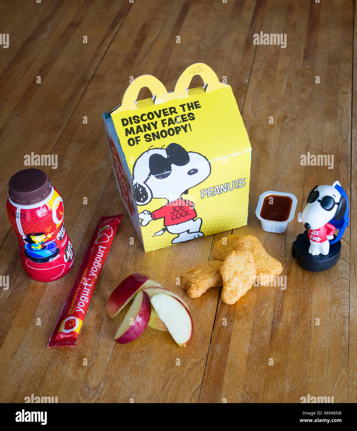 Un McDonald's Happy Meal con pollo McNuggets, apple cunei, cioccolato al latte, yogurt tubo e Snoopy giocattolo. Foto Stock