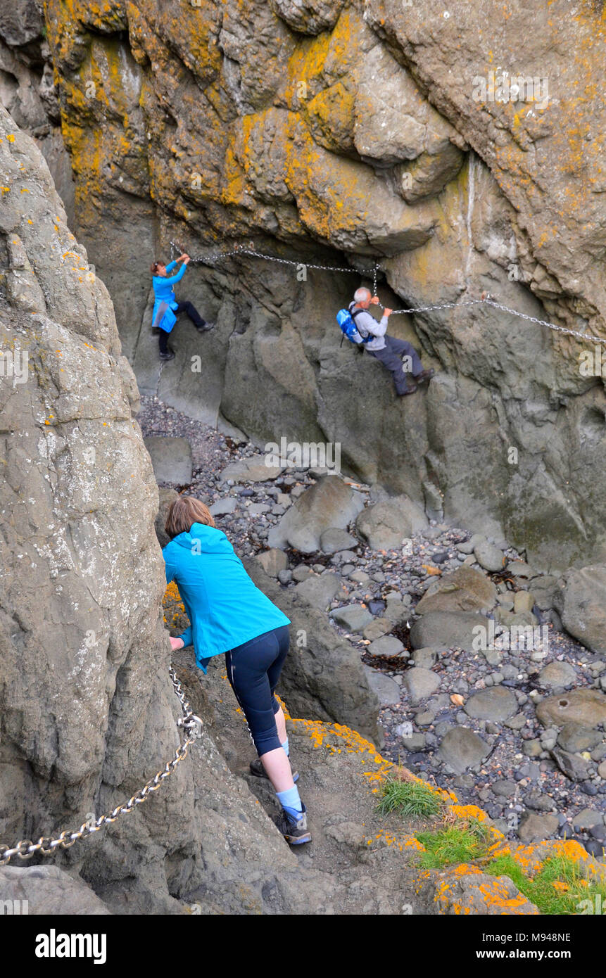 Un gruppo di persone fanno il rocky catena costiera a piedi in Elie, Fife Foto Stock