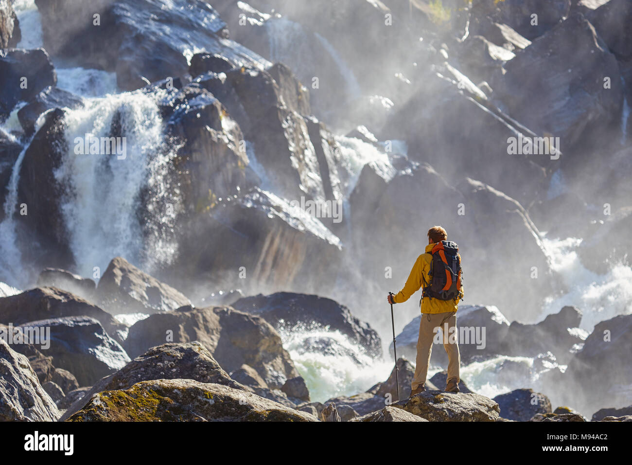 Escursionista escursionismo con zaino guardando la cascata nel parco in bella estate natura paesaggio. Ritratto di maschio adulto torna in piedi all'aperto. Foto Stock