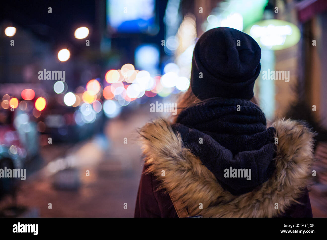 Vista posteriore di un hipster ragazza camminare sulla via della città di notte Foto Stock