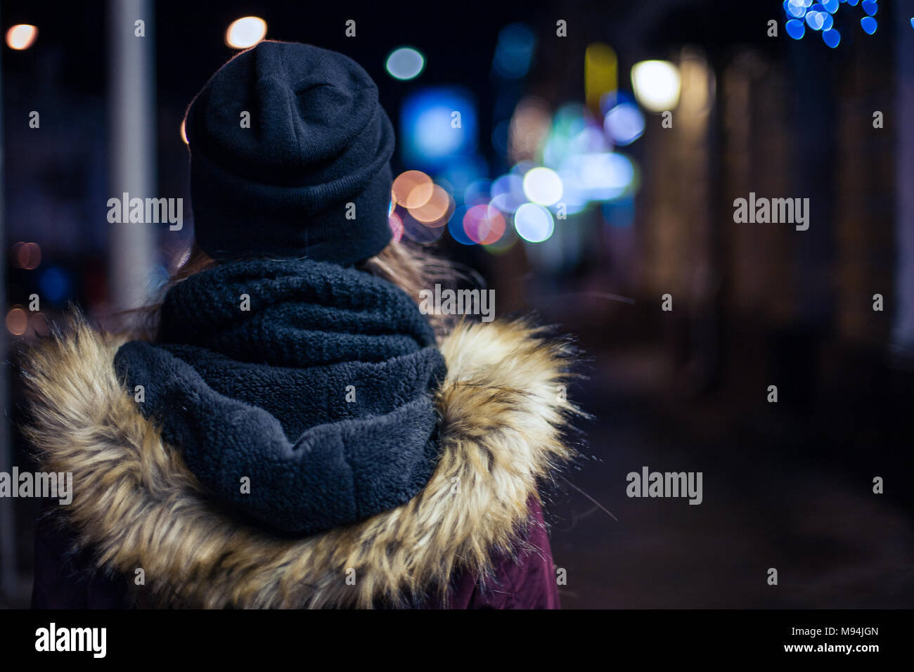 Vista posteriore di un hipster ragazza camminare sulla via della città di notte Foto Stock