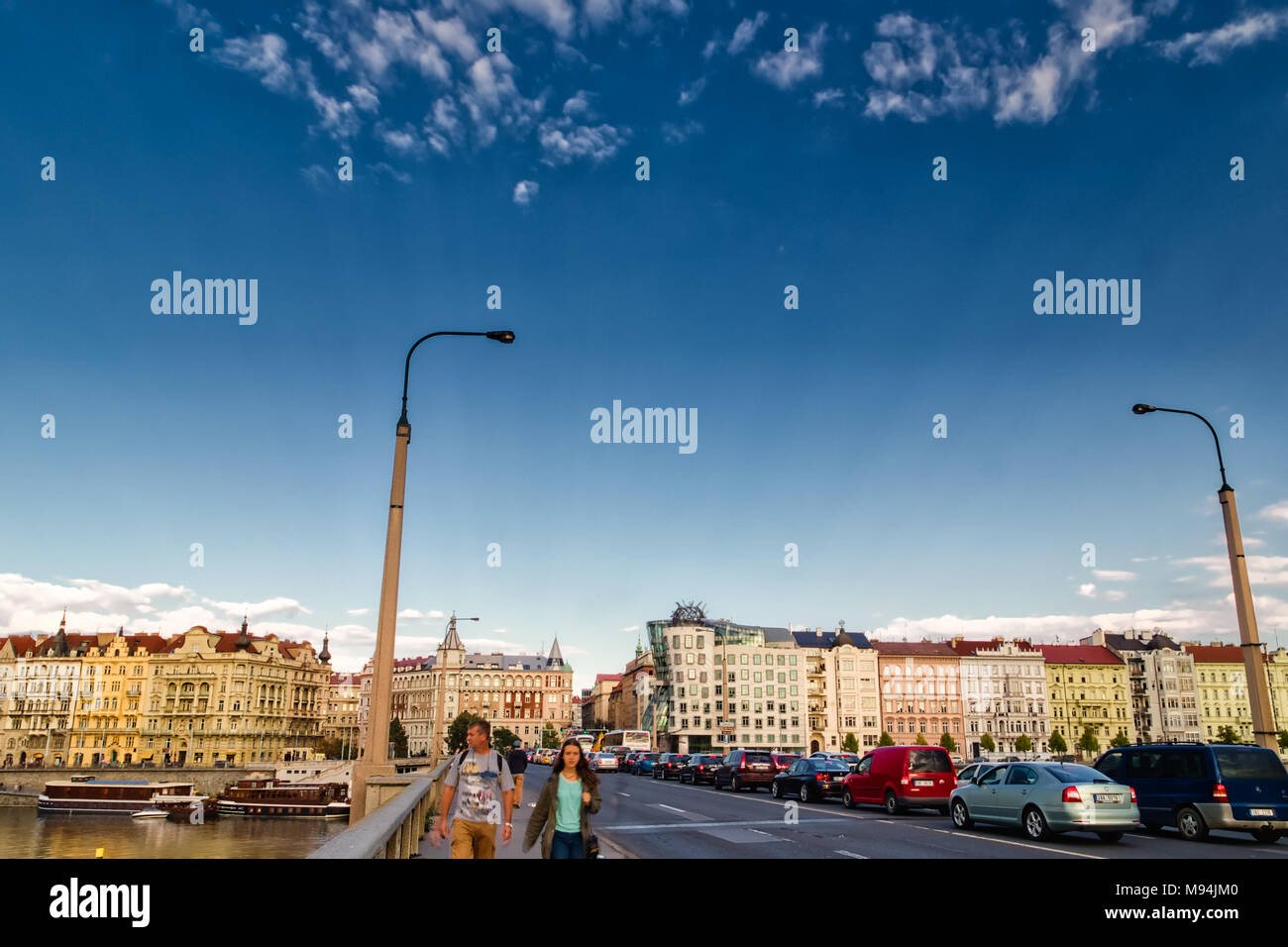 Praga, Repubblica Ceca - 27 agosto 2014: il sole illumina la Casa Danzante mentre le auto si muovono sul ponte di Praga Foto Stock