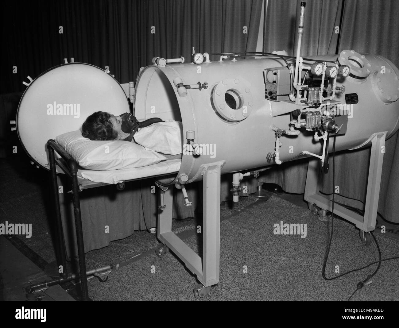 Un operatore medico dimostra un nuovo paziente con ossigeno iperbarico la camera di American College of Surgeons congresso a Chicago, ca. 1964. Foto Stock