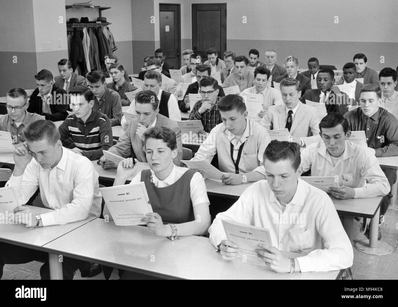 Noi studenti di scuola superiore di guardare al di sopra di un test standardizzato esame che sono in procinto di prendere, ca. 1958. Foto Stock