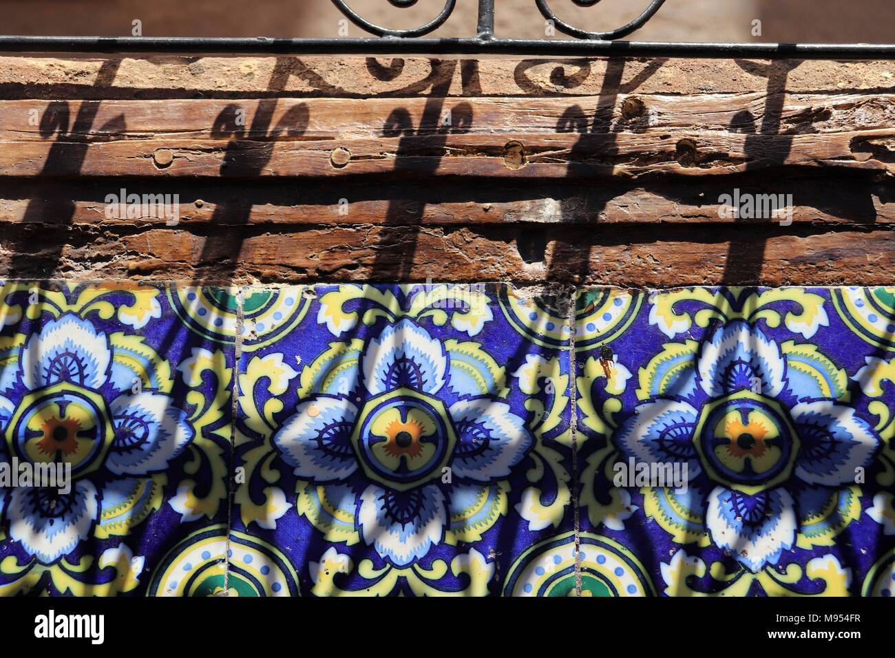 Le ombre cadono attraverso alcuni scrollwork decorativo sulla fantasia piastrelle marocchine in un Riad Foto Stock