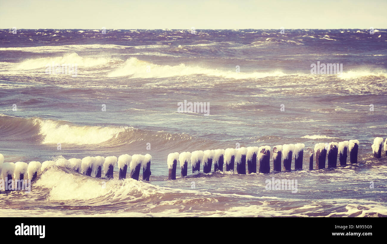 Congelati frangiflutti in legno in una giornata di vento, del Mar Baltico della Polonia, dai toni di colore dell'immagine. Foto Stock