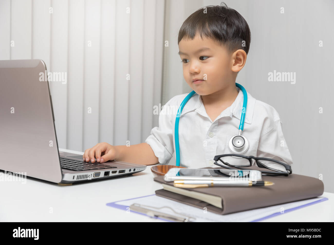 Giovane ragazzo asiatico riproduzione medico e utilizzo di computer portatile. Foto Stock