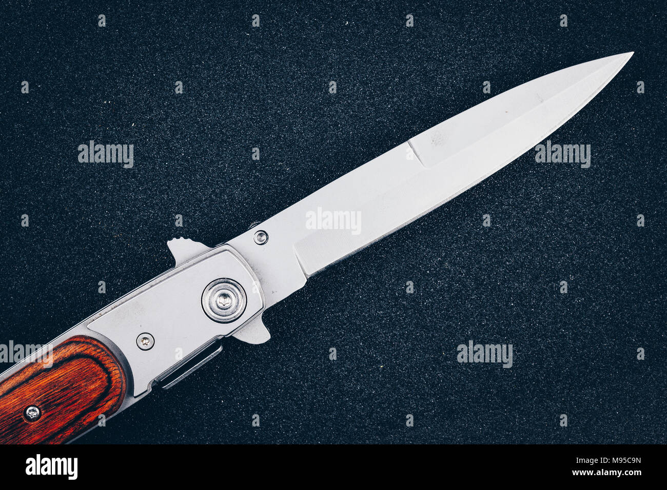 Coltello pieghevole su asfalto nero. Strumento di criminalità Foto Stock