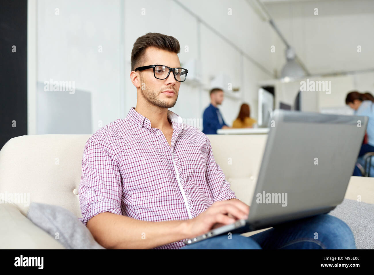 Uomo in occhiali con laptop lavorando in ufficio Foto Stock