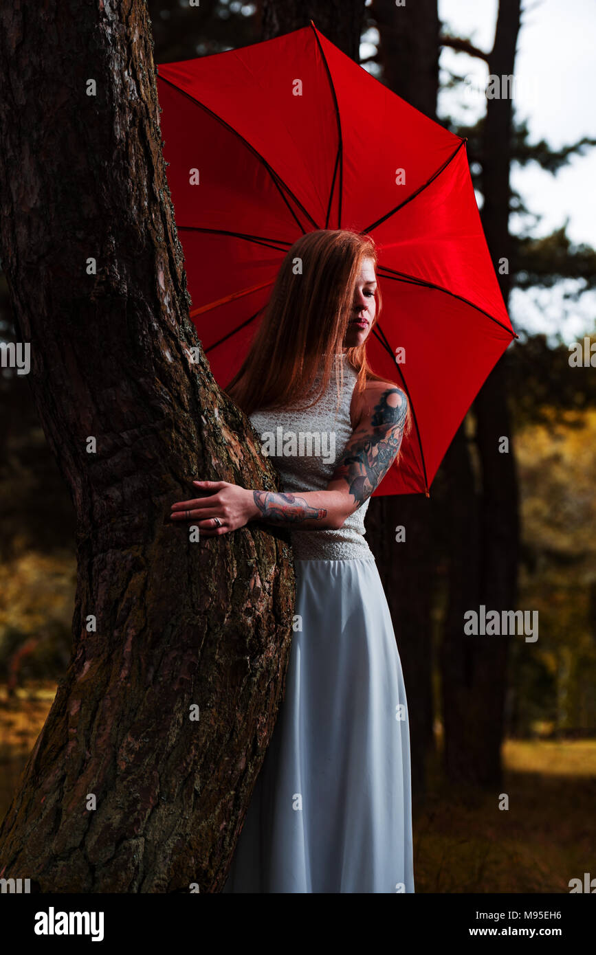 Mary Poppins e moderno concetto di moda. Bianco caucasico modello femminile  in piedi con ombrello rosso e di godere di condizioni meteorologiche. Bella  donna con capelli lunghi, in Foto stock - Alamy