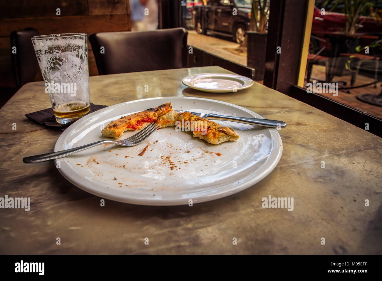 Una pizza, mangiato, solo con la crosta e una gran parte di birra vuote rimanenti. Foto Stock