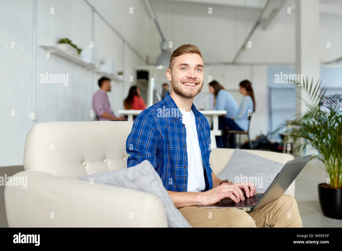Uomo sorridente con notebook lavorando in ufficio Foto Stock