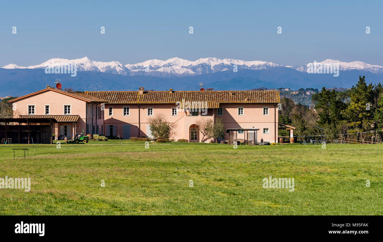 Paese e golf resort nella campagna toscana contro le montagne nevose, Pontedera, Pisa, Toscana, Italia Foto Stock