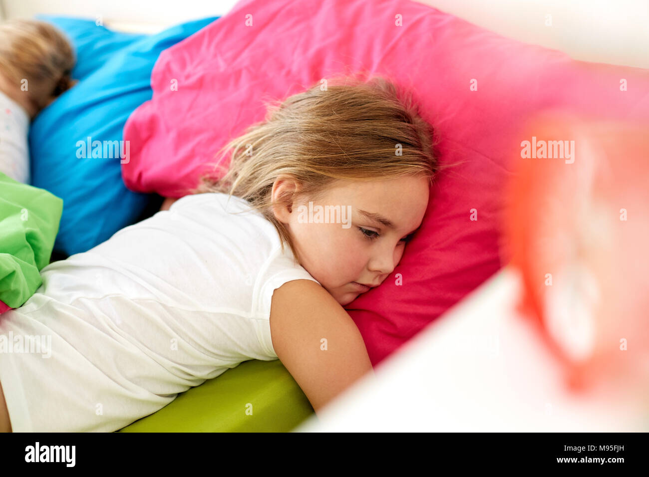 Bambina giacente svegli nel letto di casa Foto Stock