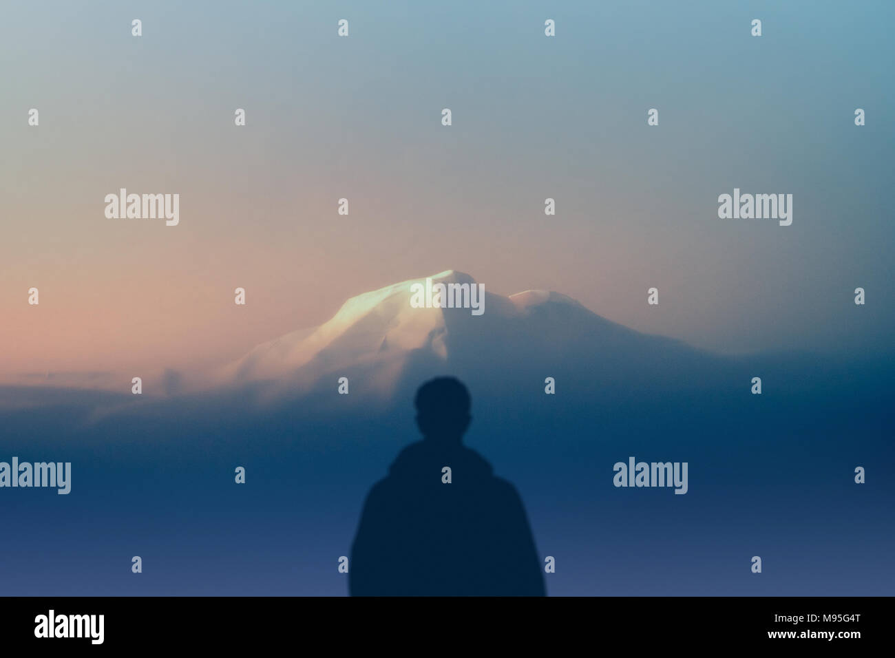 Silhouette uomo escursionista sorge all'esterno guardando di montagna più alta al tramonto. concetto natura e la razza umana. spazio copia Foto Stock