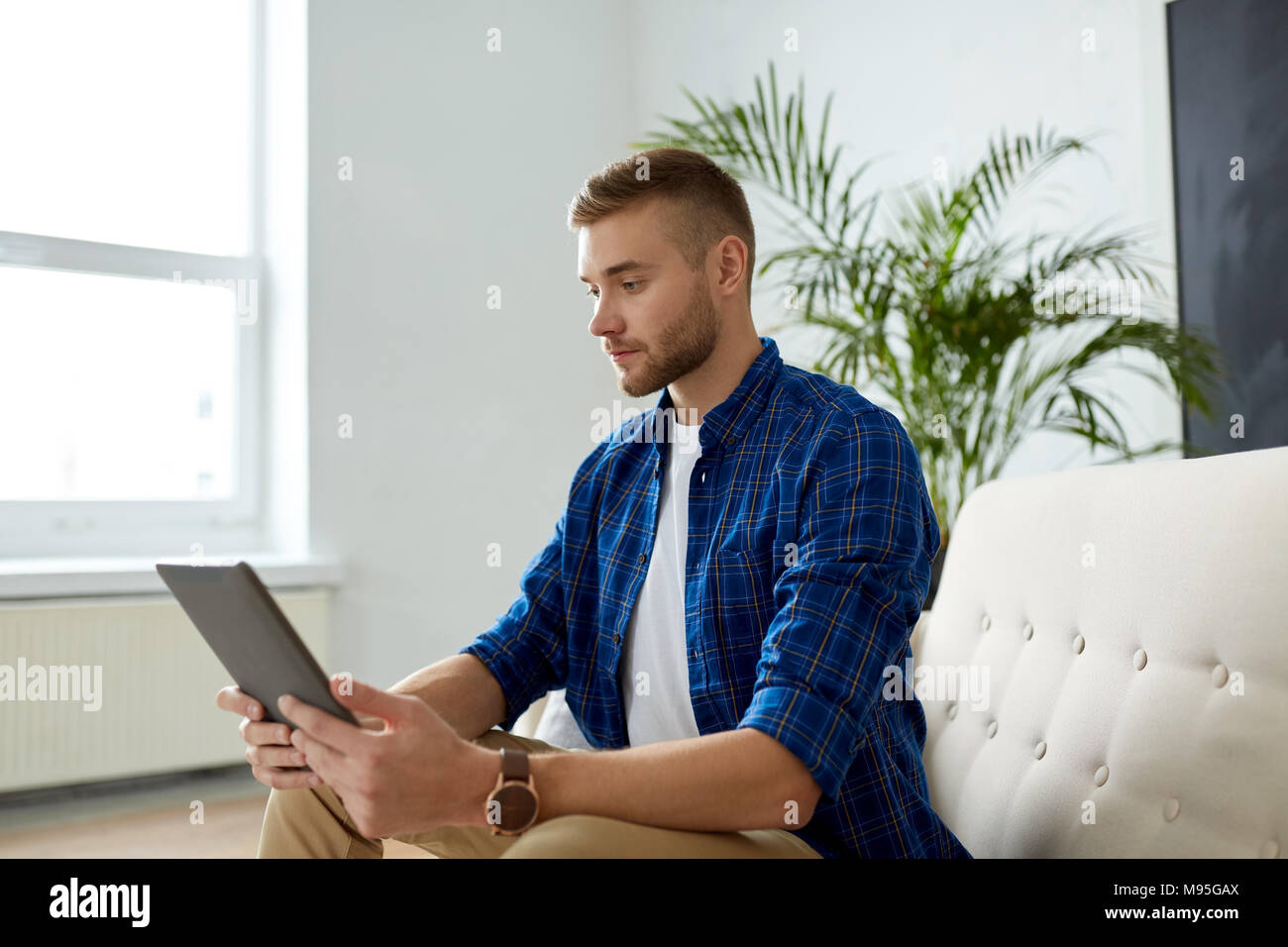 Uomo con tablet pc seduti sul divano in ufficio Foto Stock