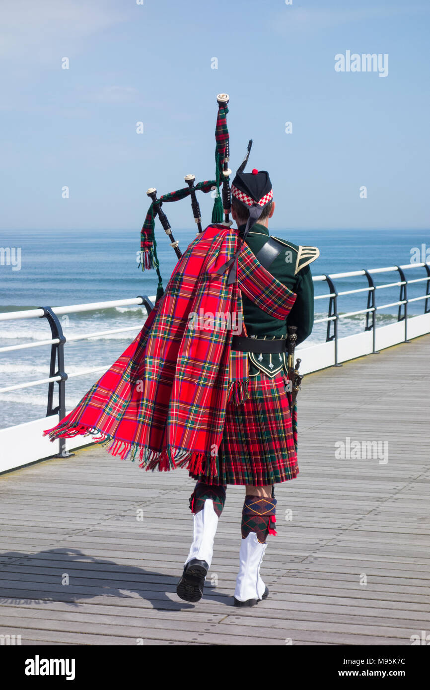 Scottish Piper in abito tradizionale su Saltburn il molo vittoriano. Saltburn dal mare, North Yorkshire, Inghilterra, Regno Unito. Foto Stock