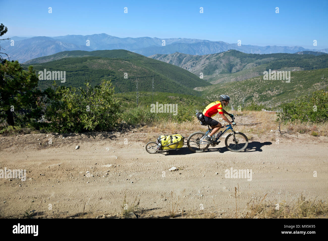 WA13918-00...WASHINGTON - mountain biker il traino di un rimorchio fino il fango Creek Road attraversando le montagne Chelan, parte della gamma di cascata. Foto Stock