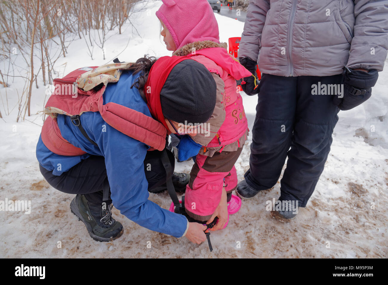 Una madre che fa le racchette da neve su una bambina di 3 anni) in Québec Canada Foto Stock