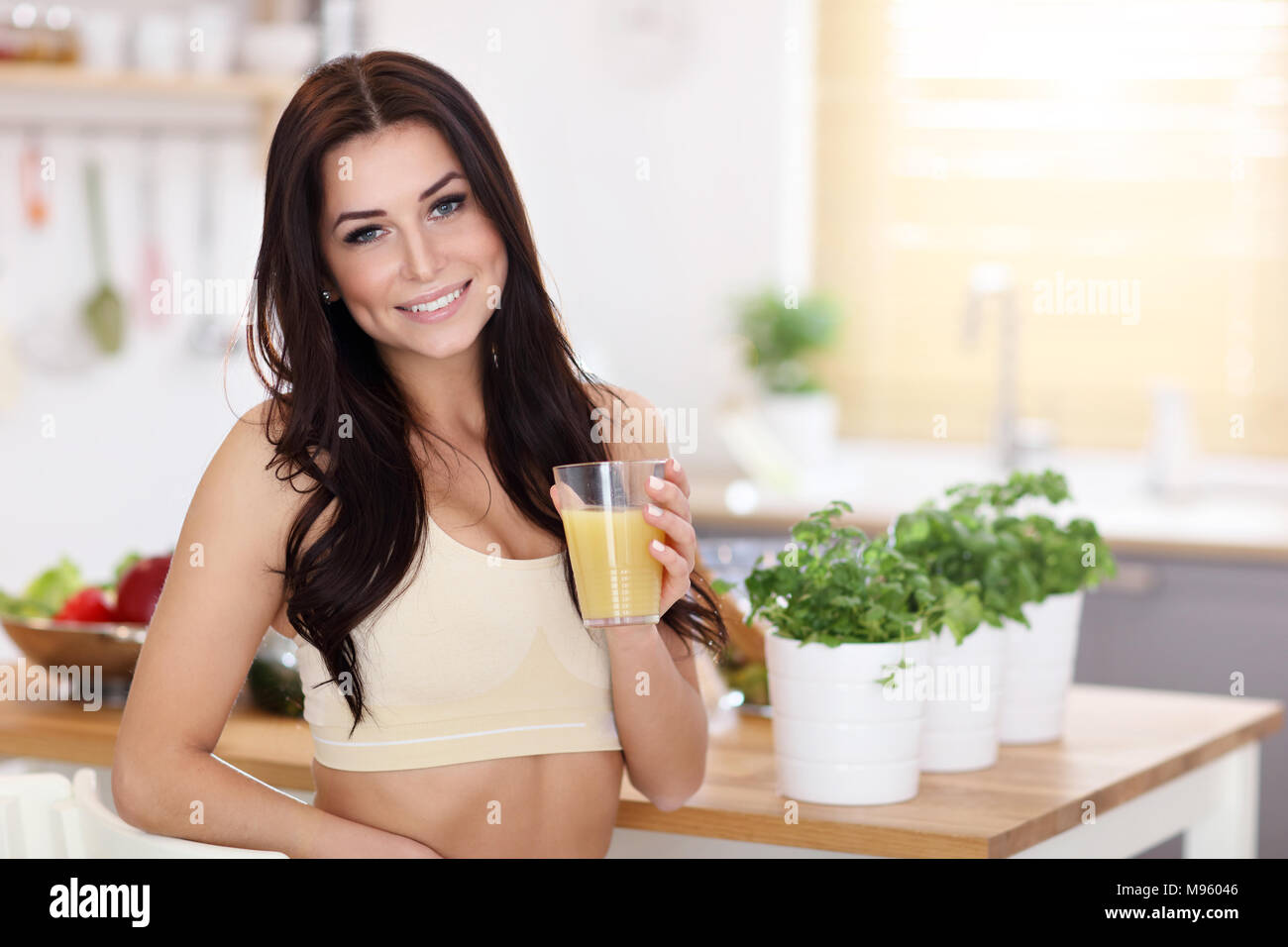 Montare sorridente giovane donna con sani succhi di frutta nella cucina moderna Foto Stock