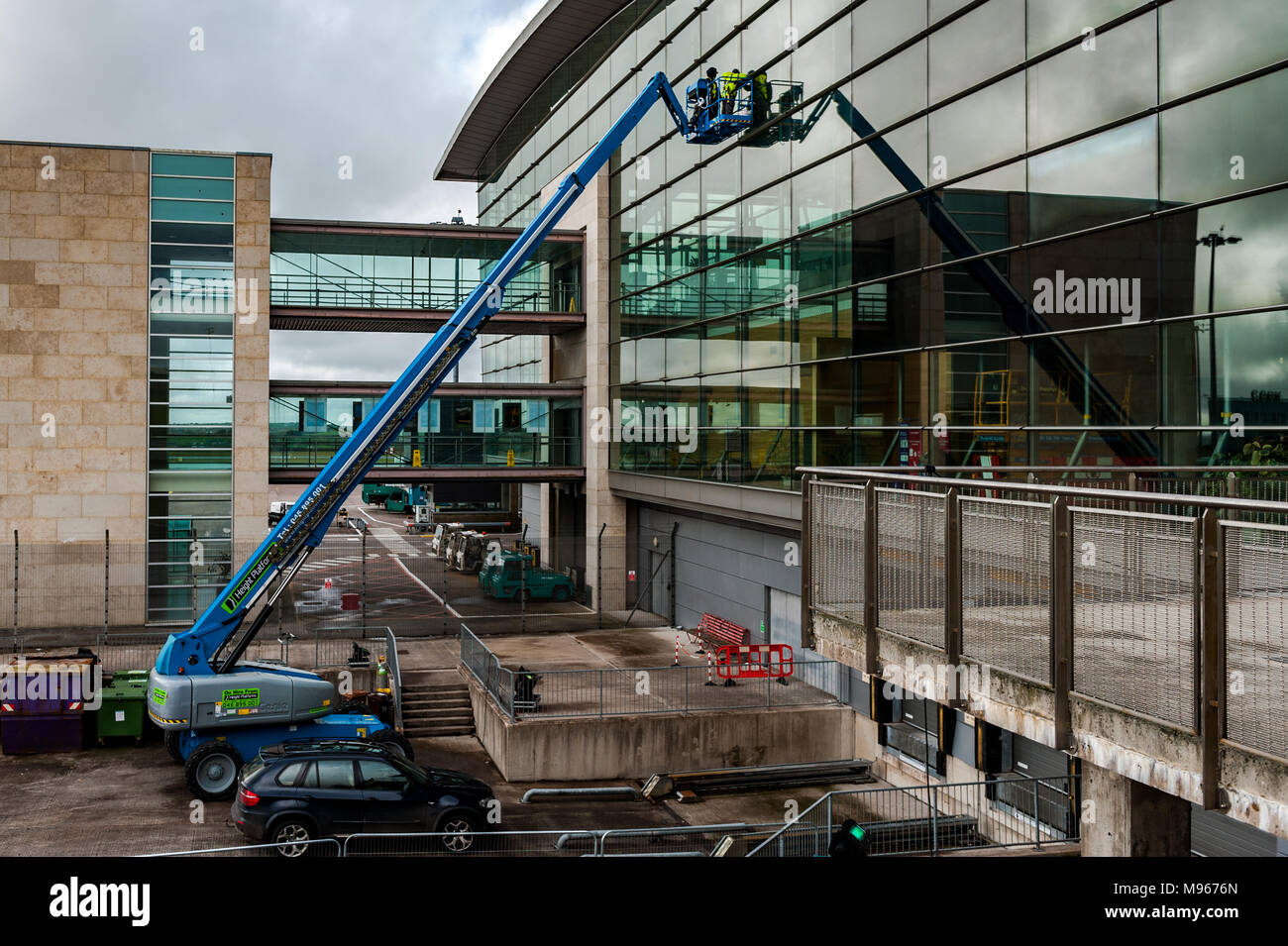 Operai su un cherry picker la riparazione di una finestra di terminale all'Aeroporto di Cork, Cork, Irlanda. Foto Stock