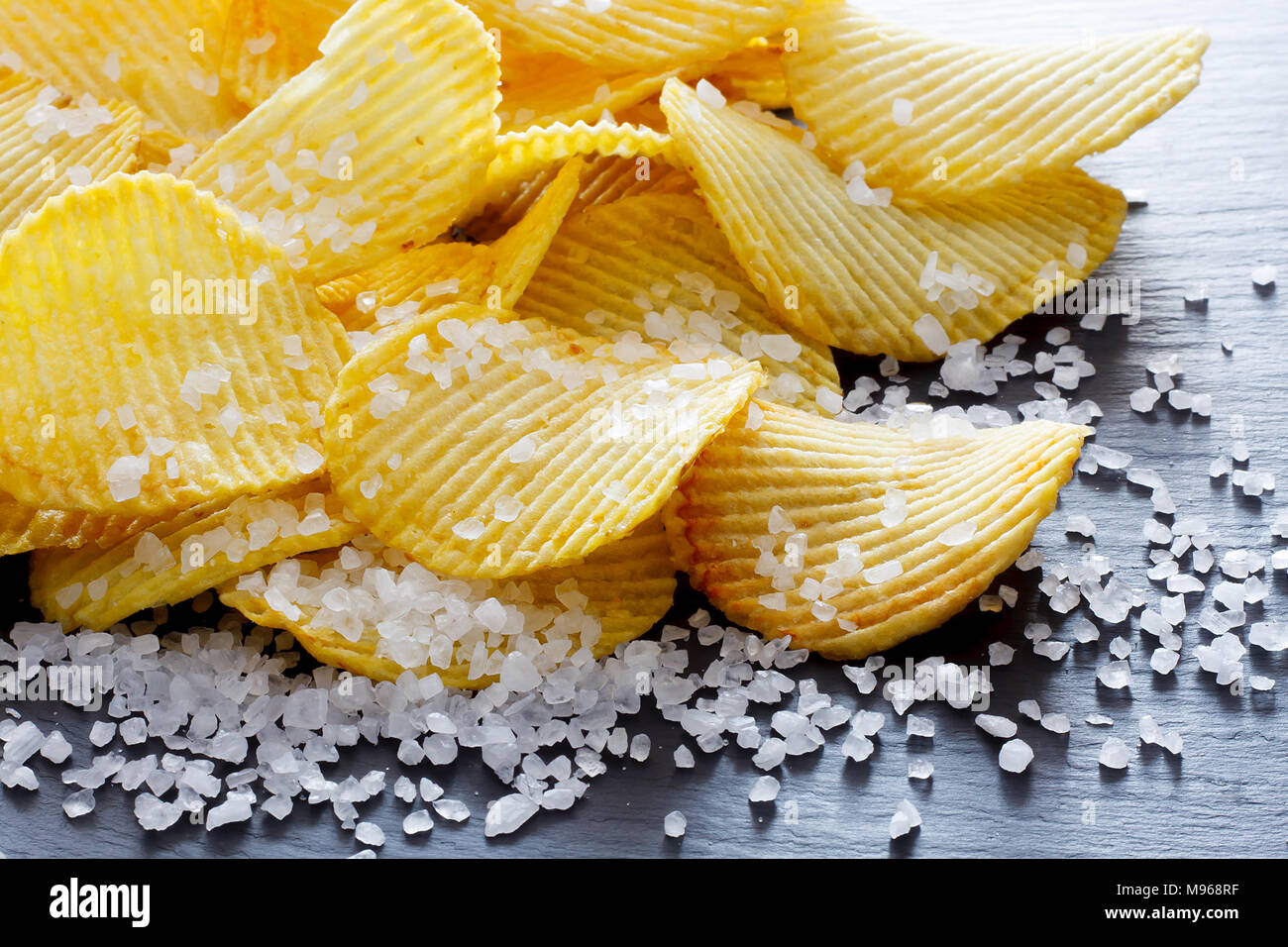 Il sale nei cibi - Le patatine e il sale. Cibo malsano concetto Foto Stock