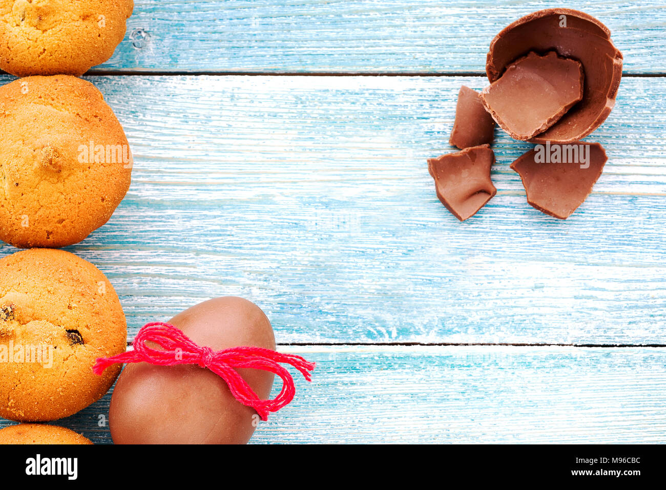 Uovo di cioccolato e muffin su un blu sullo sfondo di legno Foto Stock