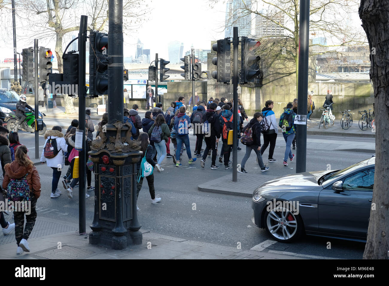 Un folto gruppo di giovani turisti attraversando una strada a Londra. Foto Stock