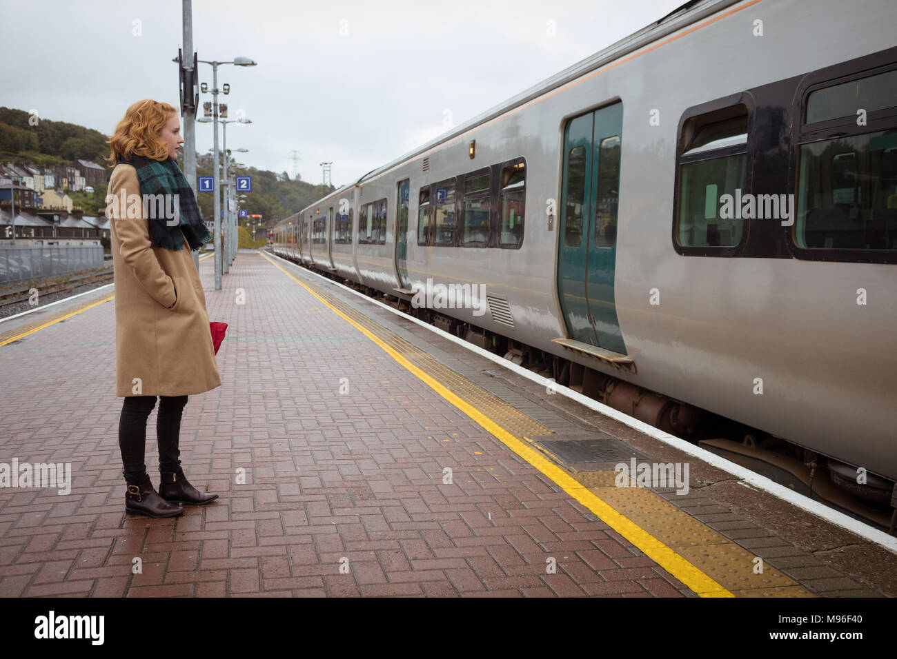 Bella giovane donna in piedi sulla piattaforma nella parte anteriore del treno Foto Stock