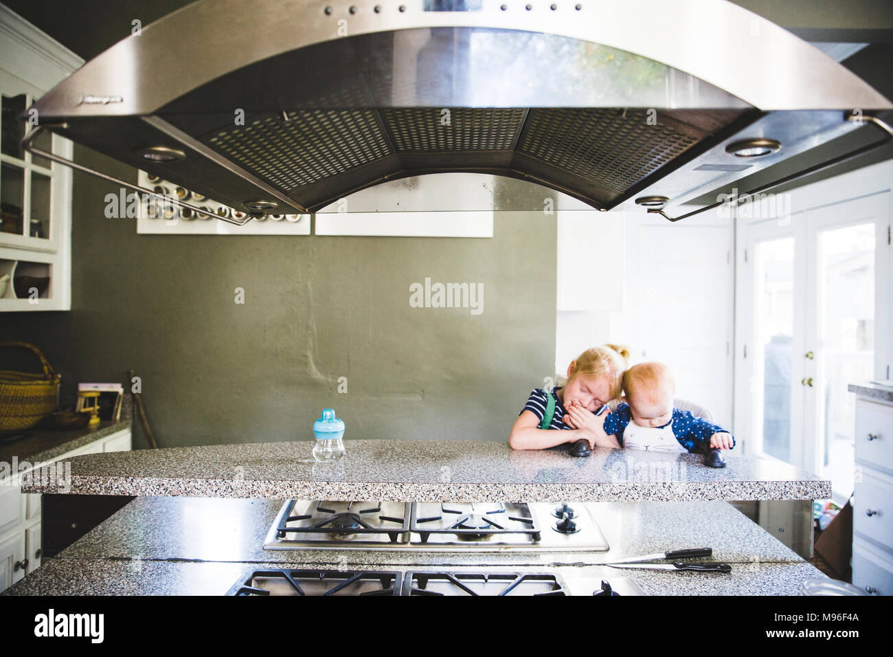 La ragazza e il bambino seduto al banco di cucina Foto Stock