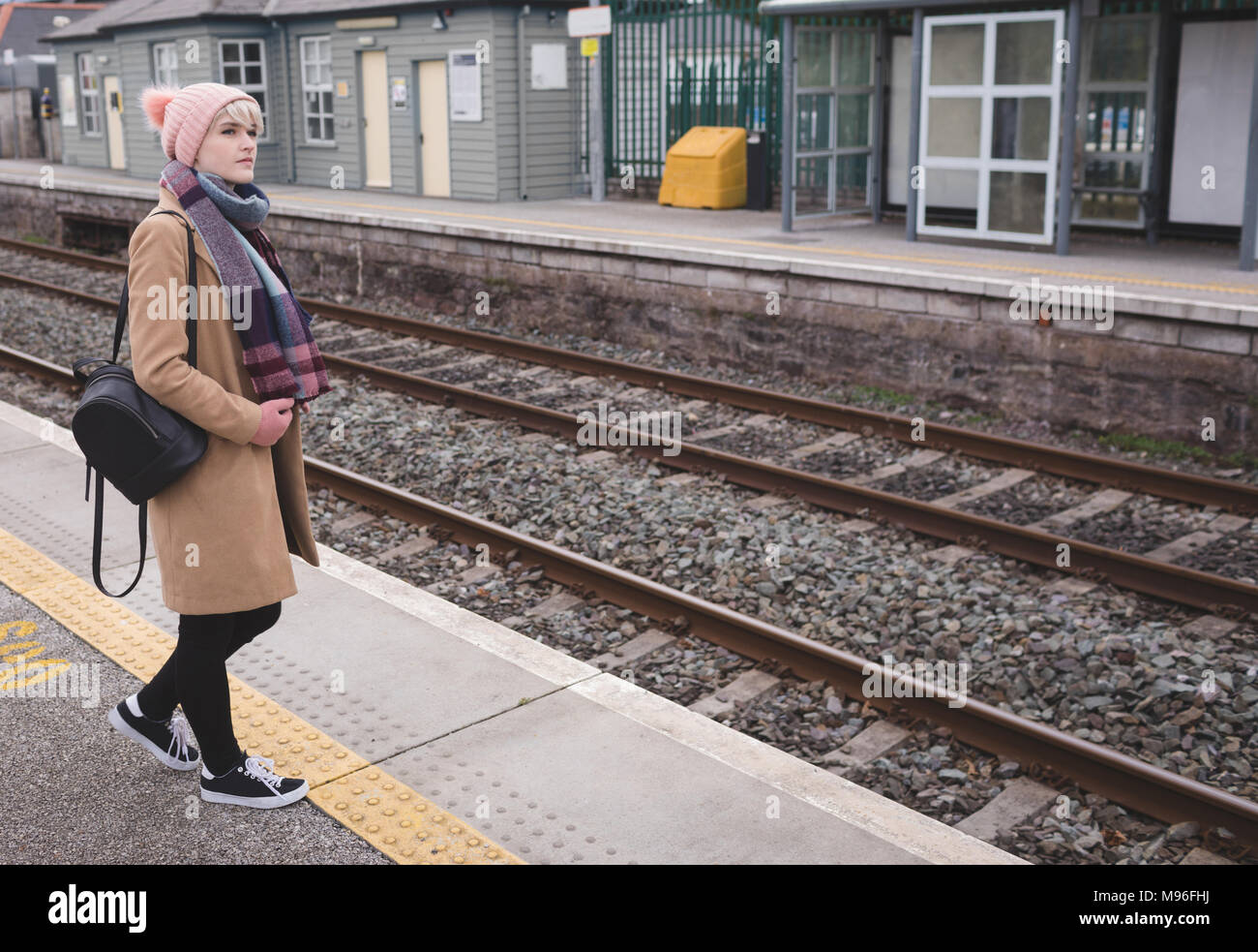 La donna in attesa del treno in stazione ferroviaria Foto Stock