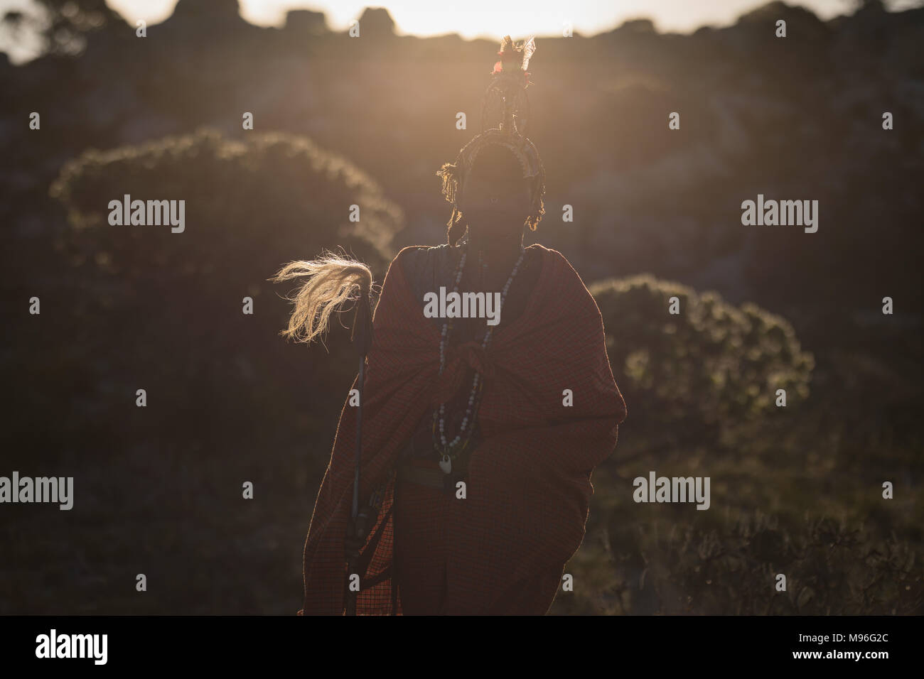 Maasai uomo in abbigliamento tradizionale in piedi con bastone Foto Stock