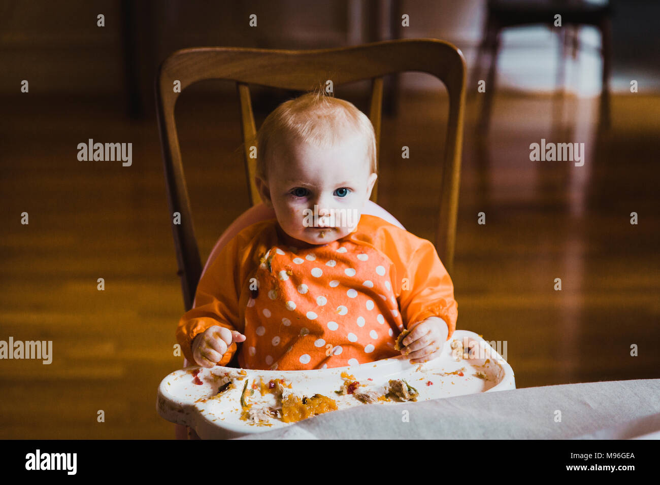 Baby facendo un pasticcio di mangiare in sedia alta Foto Stock