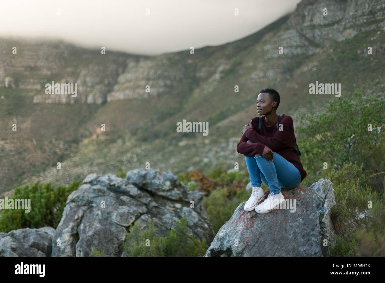 Donna seduta su una roccia a campagna Foto Stock