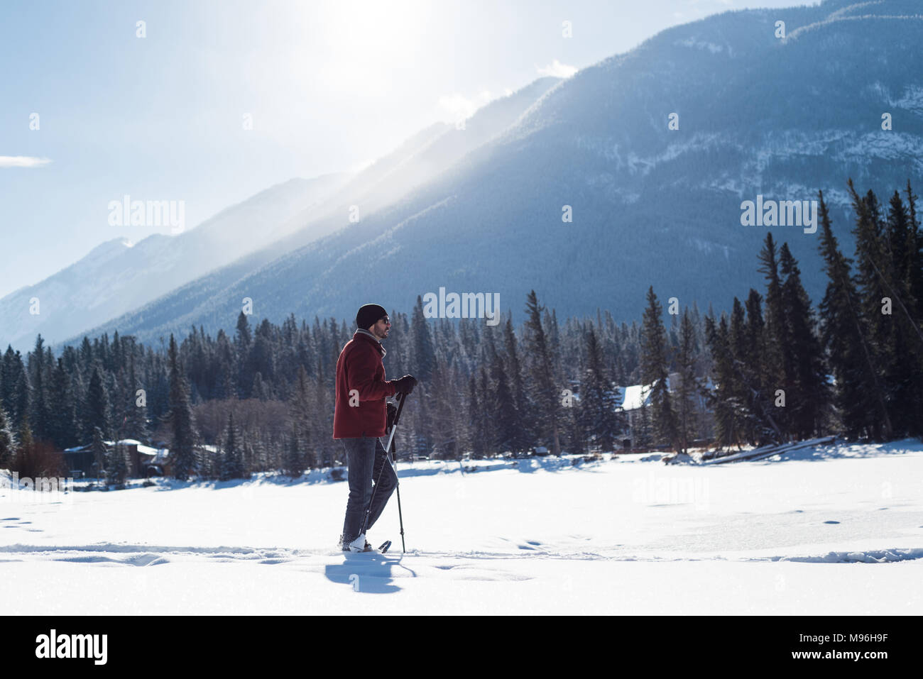Uomo che cammina con bastoncini da sci nel paesaggio innevato Foto Stock