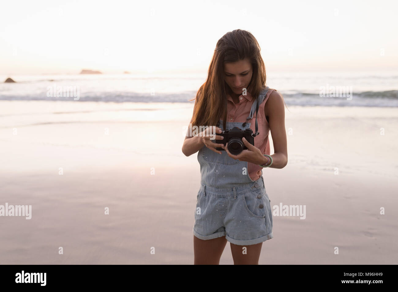 Donna tenere la fotocamera in spiaggia Foto Stock