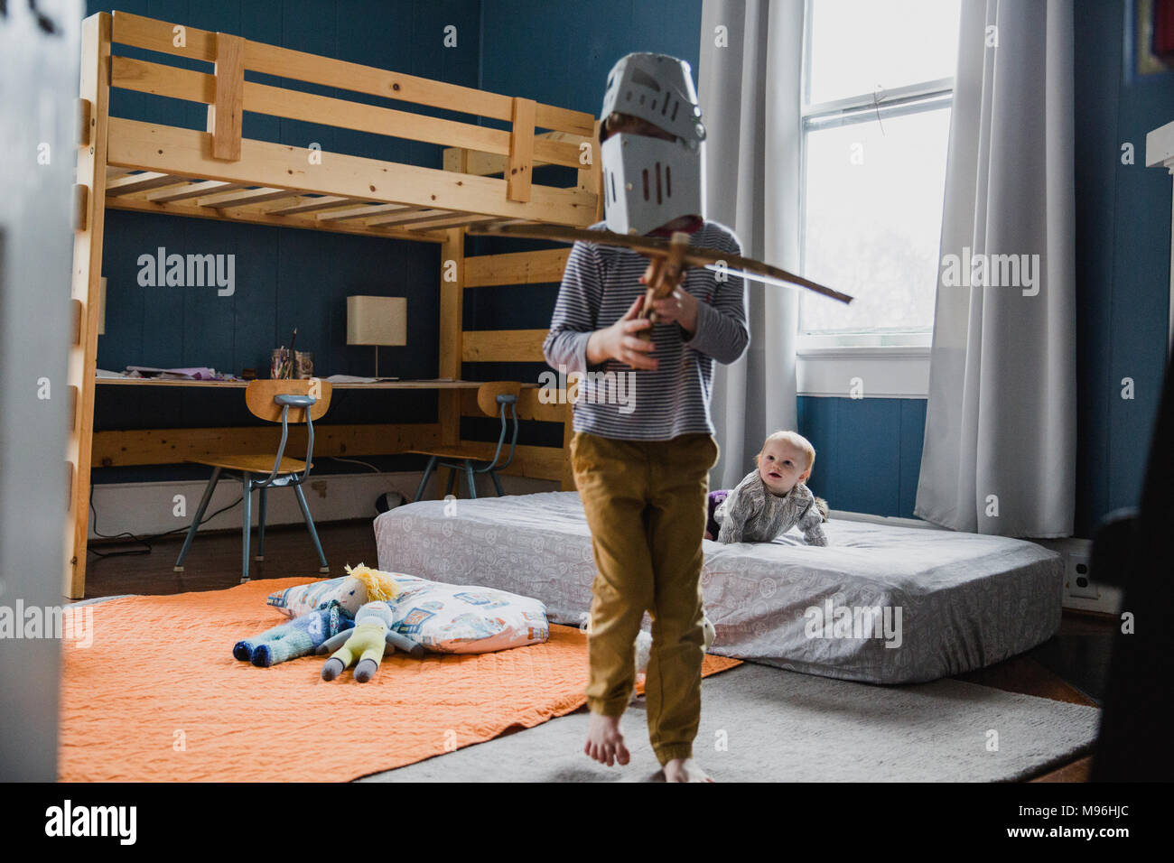Ragazzo con cavaliere del casco in piedi in camera da letto Foto Stock