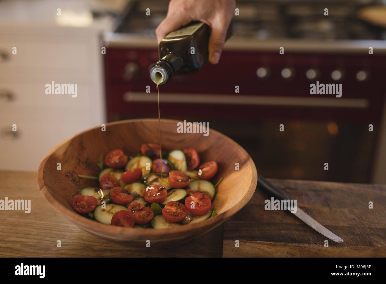 L'uomo versando olio commestibile su vegetali in cucina Foto Stock