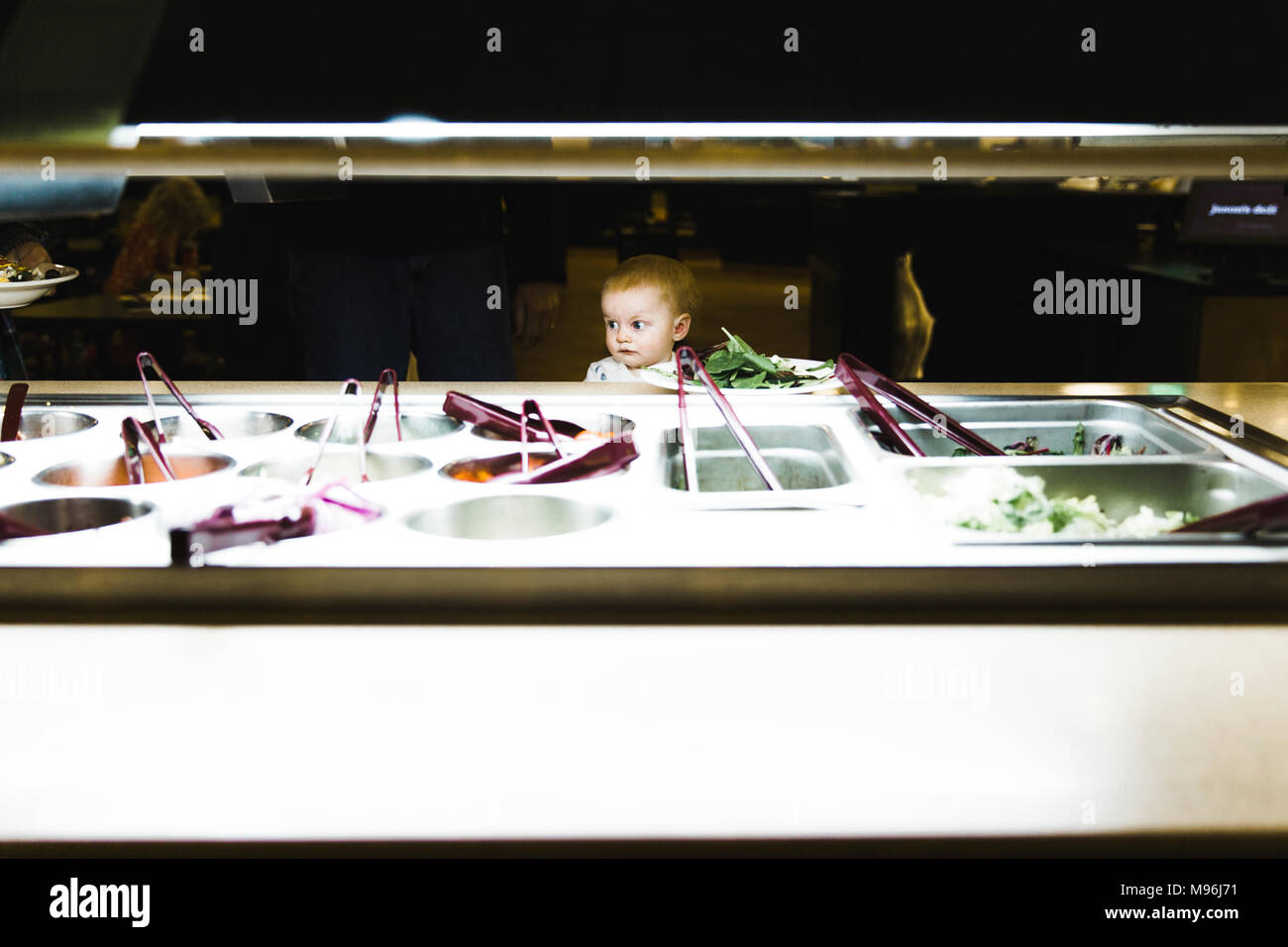 Il bambino che si affaccia su un salad bar Foto Stock