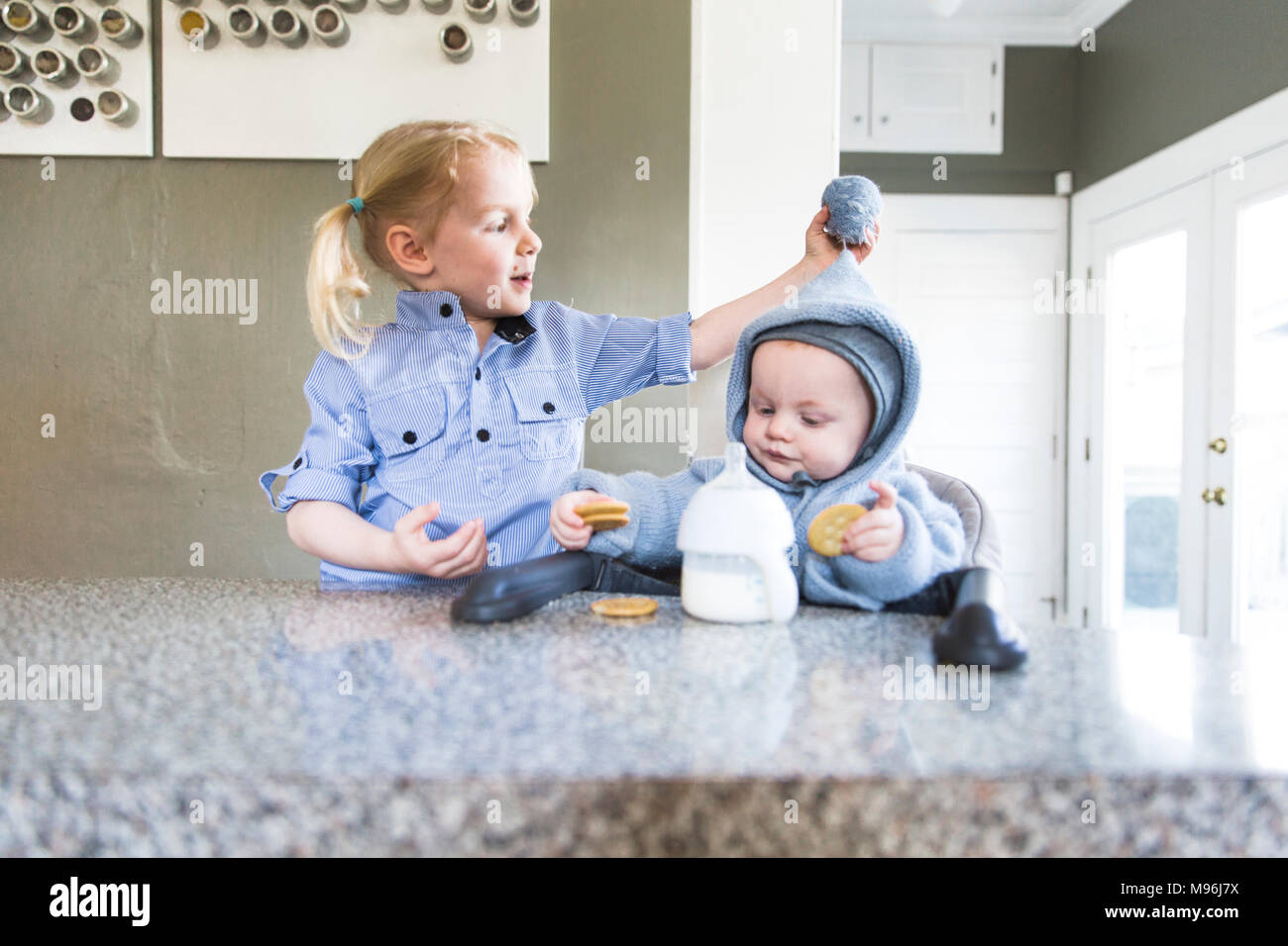 La ragazza e il bambino vestito di blu al banco di cucina Foto Stock