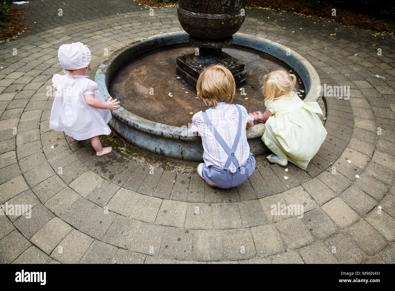 Il bambino e gli altri bambini che giocano intorno a fontana Foto Stock