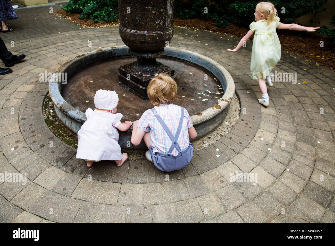 Il bambino e gli altri bambini che giocano intorno a fontana Foto Stock