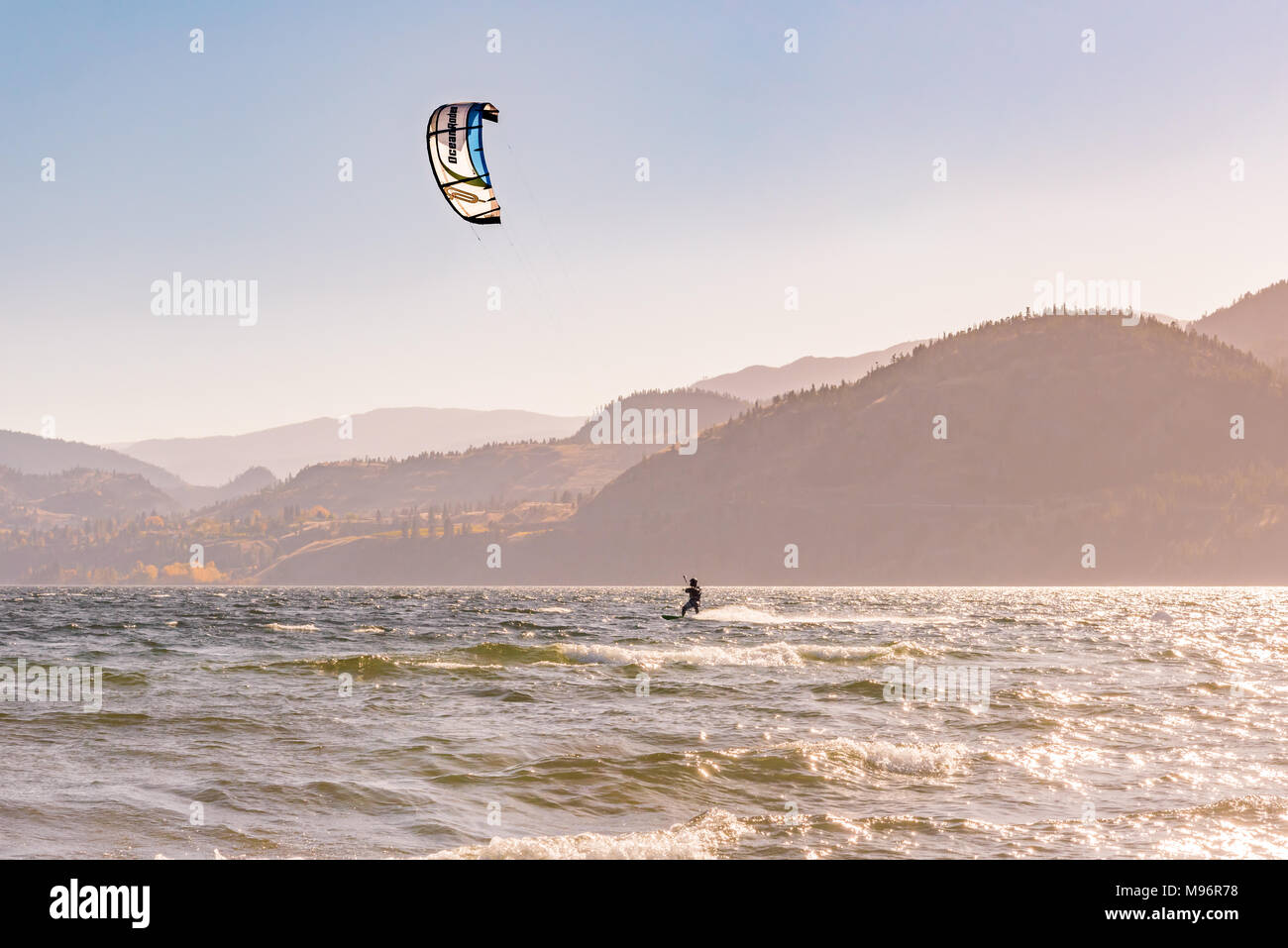 Un uomo su un kiteboard naviga attraverso il Lago Skaha a Penticton, British Columbia, Canada, su una soleggiata giornata autunnale. Foto Stock