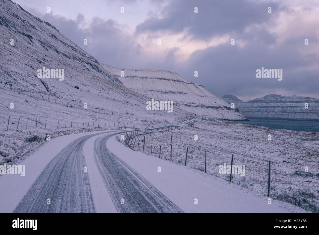 Una coperta di neve strada nelle isole Faerøer Foto Stock
