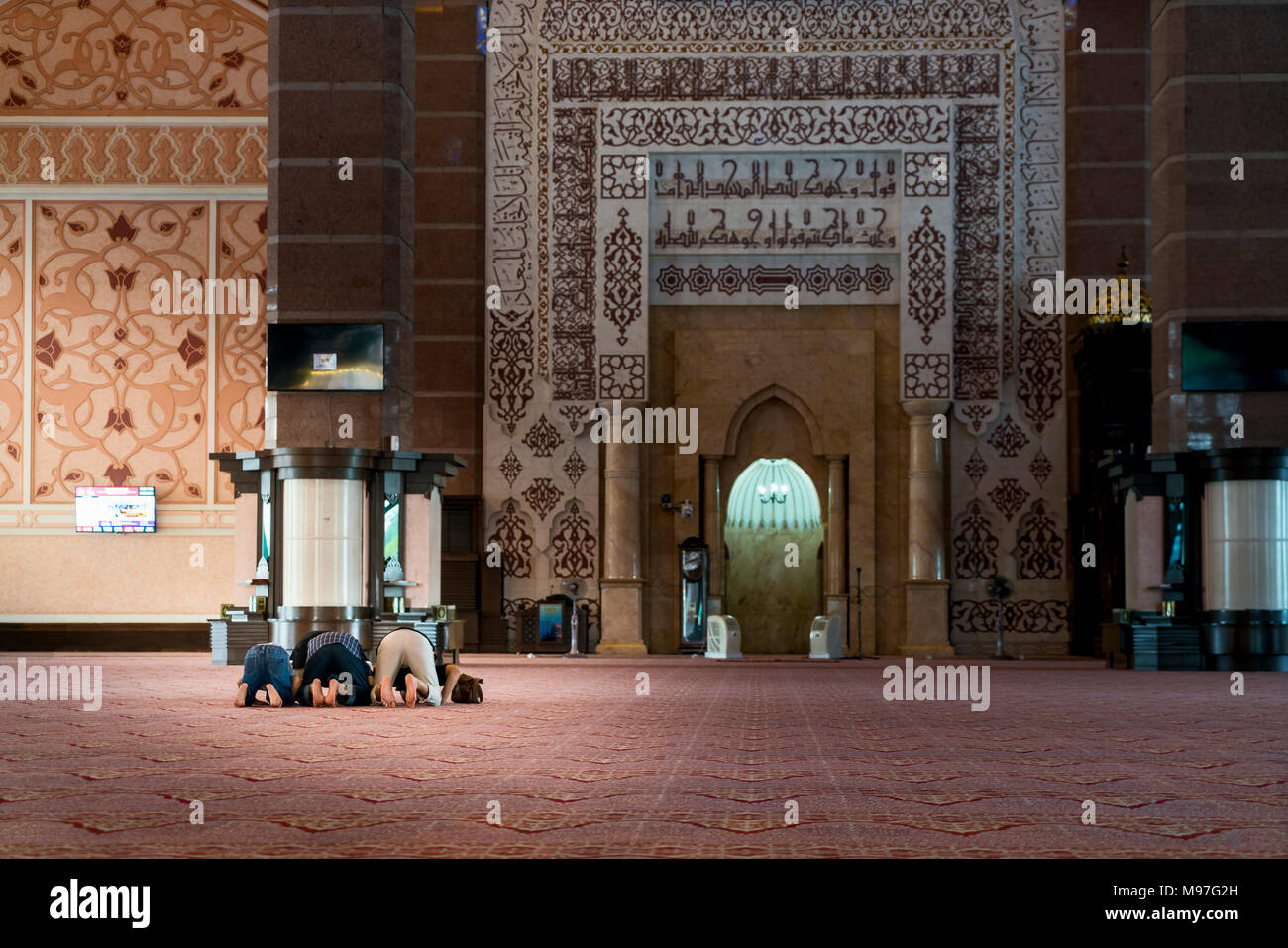 Gruppo di religiosi musulmani pregano l'uomo all'interno della moschea. Preghiera islamica, prostrarsi a terra. Foto Stock