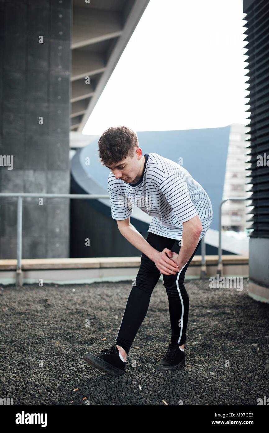 Freerunner è il suo stiramento dei muscoli delle gambe su un tetto. Foto Stock